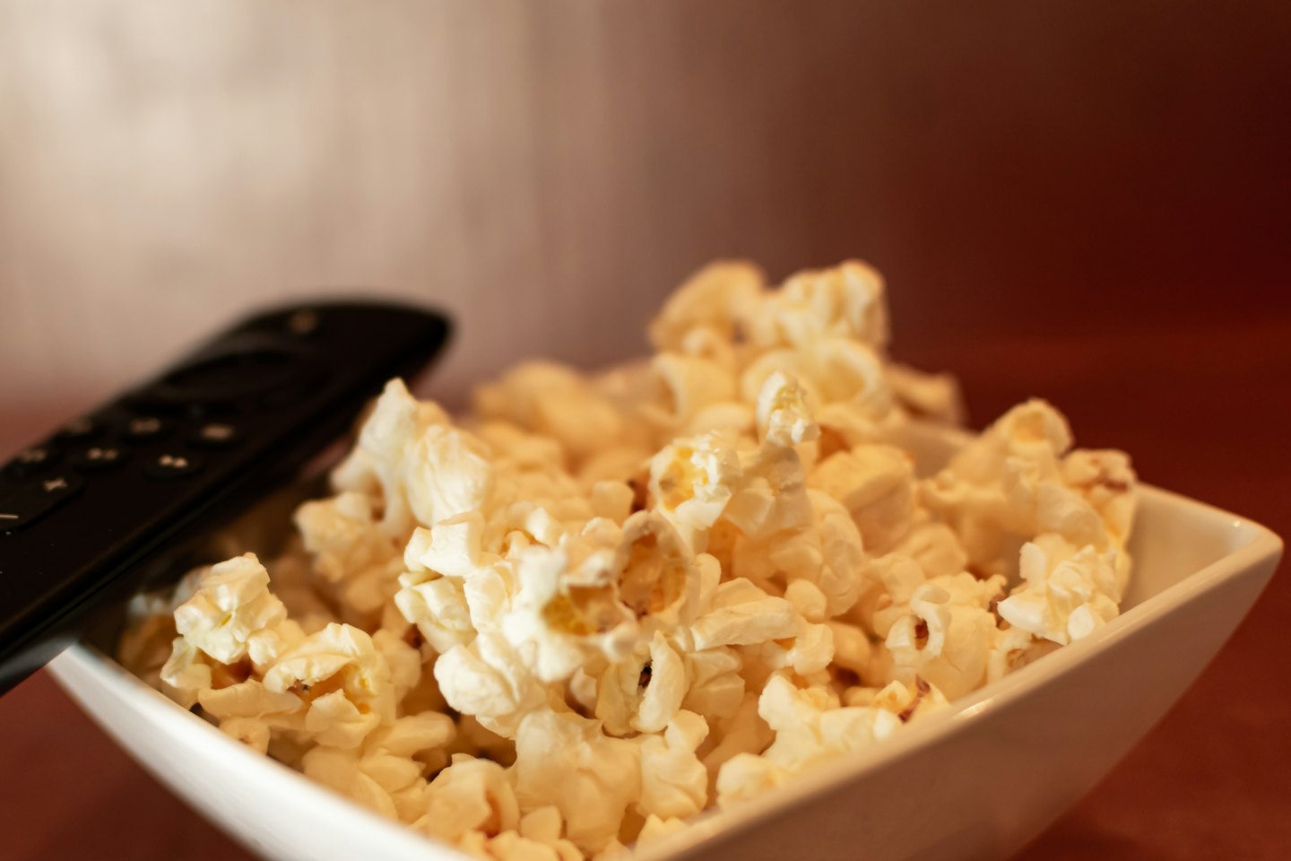 Eine Schüssel Popcorn steht auf einer braunen Oberfläche.